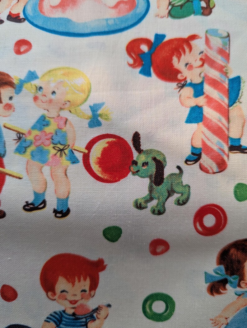 May include: White fabric with a repeating pattern of vintage children, candy, and a green dog. The children are depicted with pigtails and bows, holding lollipops and candy canes. Red, green, and blue accents are used throughout the design.