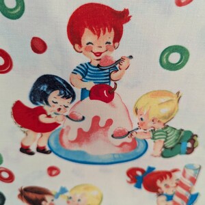 May include: A fabric print featuring a vintage illustration of children enjoying a dessert. The image shows a boy with red hair and a blue striped shirt eating from a pink dessert. Other children are also eating the dessert. Green and red candies are scattered around the image.