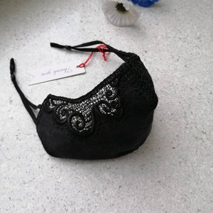 May include: Black face mask with delicate lace detailing. The mask has adjustable straps and a tag that says "Thank you".