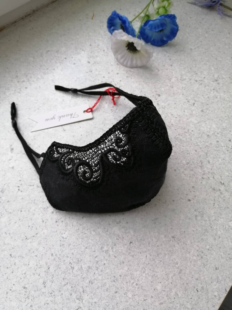 May include: Black face mask with delicate lace detailing. The mask has adjustable straps and a tag that says "Thank you".