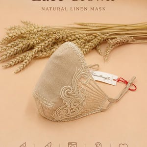 May include: A beige linen face mask featuring intricate lace detailing on the side, adjustable ear loops, and a white tag labelled Handmade. The text Design 5, Lace Crown, Natural Linen Mask, and Handmade in Ukraine is visible.