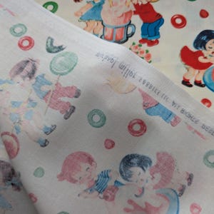May include: Two pieces of fabric with a vintage children's print. One fabric features a repeating pattern of children playing with a large drink, and the other fabric has a pattern of children with balloons and circles in red, green, and blue. The fabric is off-white.