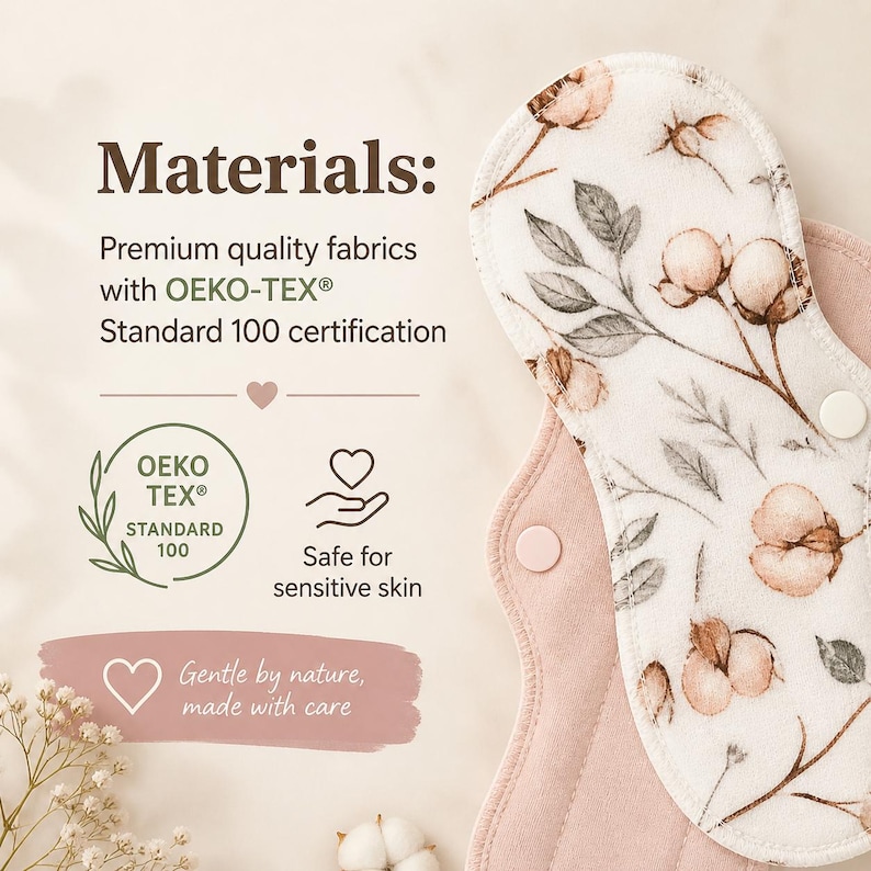 May include: A reusable cloth menstrual pad featuring a cream-colored top layer with a brown and green cotton flower print and a solid dusty pink underside. The pad includes two white snap fasteners and text stating Materials, OEKO-TEX Standard 100.
