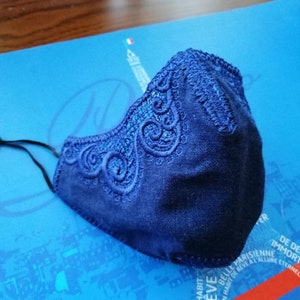 May include: A blue face mask with a lace design. The mask is made of a soft, breathable fabric and has a comfortable fit.