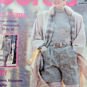 Op de afbeelding: Een tijdschriftcover met een vrouw die een grijze trui met rolkraag, een witte bontkraag en een geruite rok draagt. Het tijdschrift heet "Buro" en de tekst op de omslag luidt "Lista Przebojów" en "Najciekawsze propozycje na sezon jesień/zima '93".