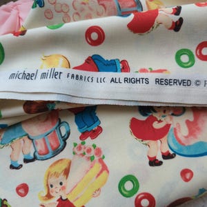 May include: Off-white fabric with a repeating pattern of children, cakes, and candies in red, blue, green, and yellow. The fabric includes the text "michael miller FABRICS LLC. ALL RIGHTS RESERVED".