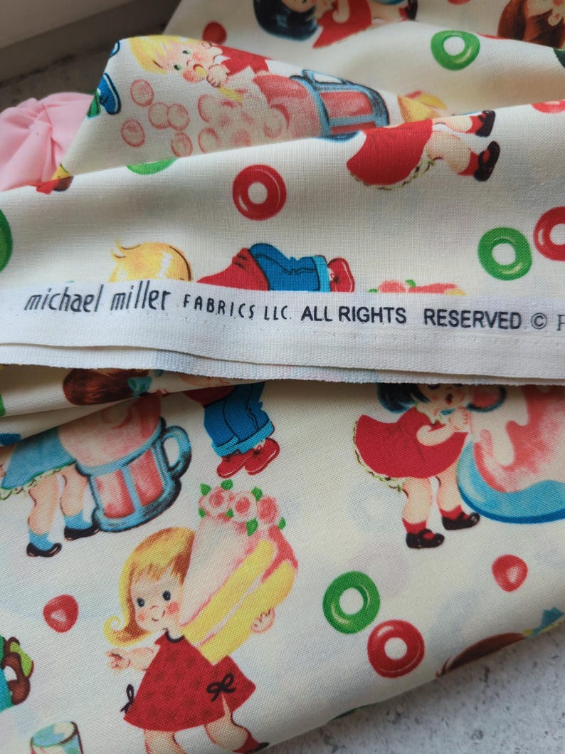 May include: Off-white fabric with a repeating pattern of children, cakes, and candies in red, blue, green, and yellow. The fabric includes the text "michael miller FABRICS LLC. ALL RIGHTS RESERVED".