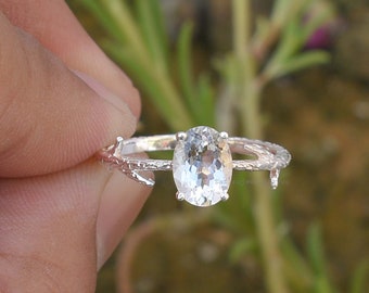 May include: A silver ring with a clear oval gemstone set in a branch-like design.