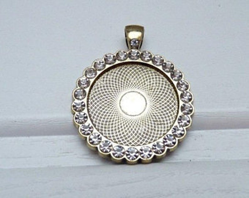 May include: Gold-toned pendant with a clear glass insert surrounded by clear rhinestones.