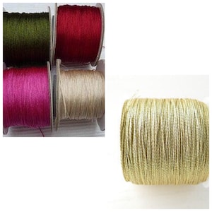 May include: Four spools of thread in different colours: green, red, pink, and beige. The thread is wound around the spools and is ready to be used for sewing or crafting.