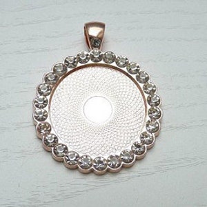 May include: Rose gold pendant with a clear round bezel and a border of clear rhinestones.