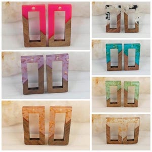 Könnte beinhalten: Zehn Paare Ohrringe aus Harz und Holz. Jedes Paar hat eine rechteckige Form mit einer anderen Farbe und einem anderen Muster aus Harz. Das Harz ist klar mit verschiedenen Farben und Mustern, darunter Pink, Lila, Blau, Grün und Weiß. Das Holz ist dunkelbraun.