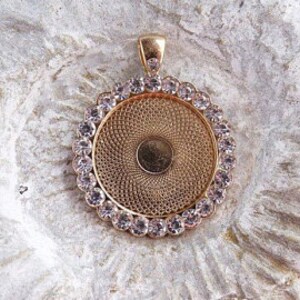 May include: Gold-toned pendant with a round, clear glass insert surrounded by a ring of clear rhinestones.