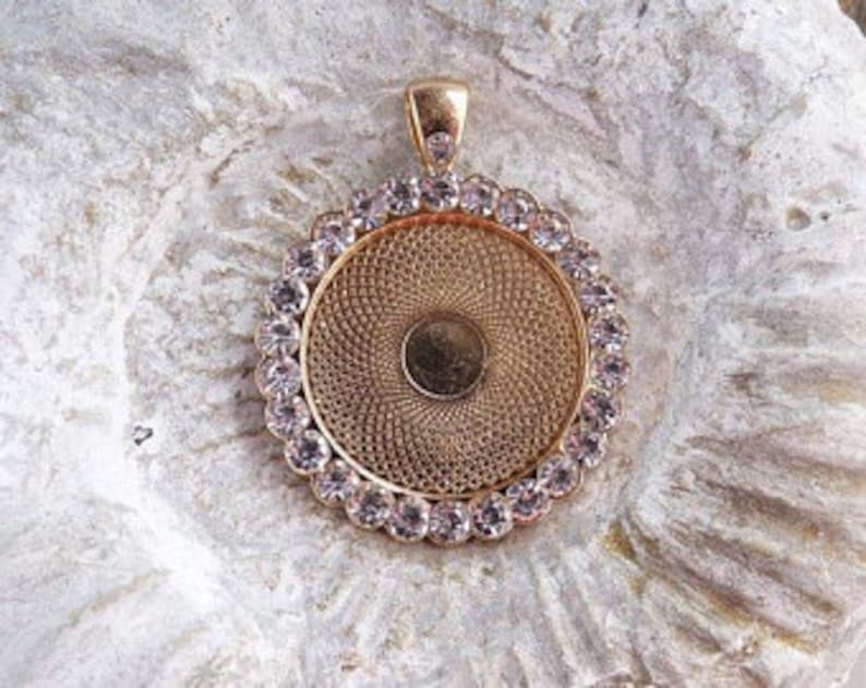 May include: Gold-toned pendant with a round, clear glass insert surrounded by a ring of clear rhinestones.