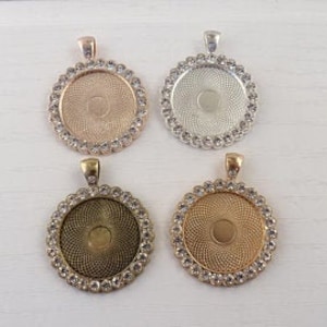 May include: Four round pendant trays with a clear rhinestone border. The trays are in four different metal finishes: rose gold, silver, antique brass, and gold.