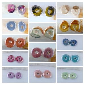 Könnte beinhalten: Sortiment von 20 bunten Keramikperlen in Donutform mit verschiedenen Mustern und Farben. Die Perlen haben einen Durchmesser von etwa 2,5 cm.