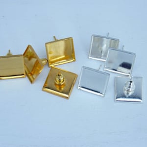 May include: Six square-shaped earring bases, three gold and three silver, with posts for attaching earring findings.