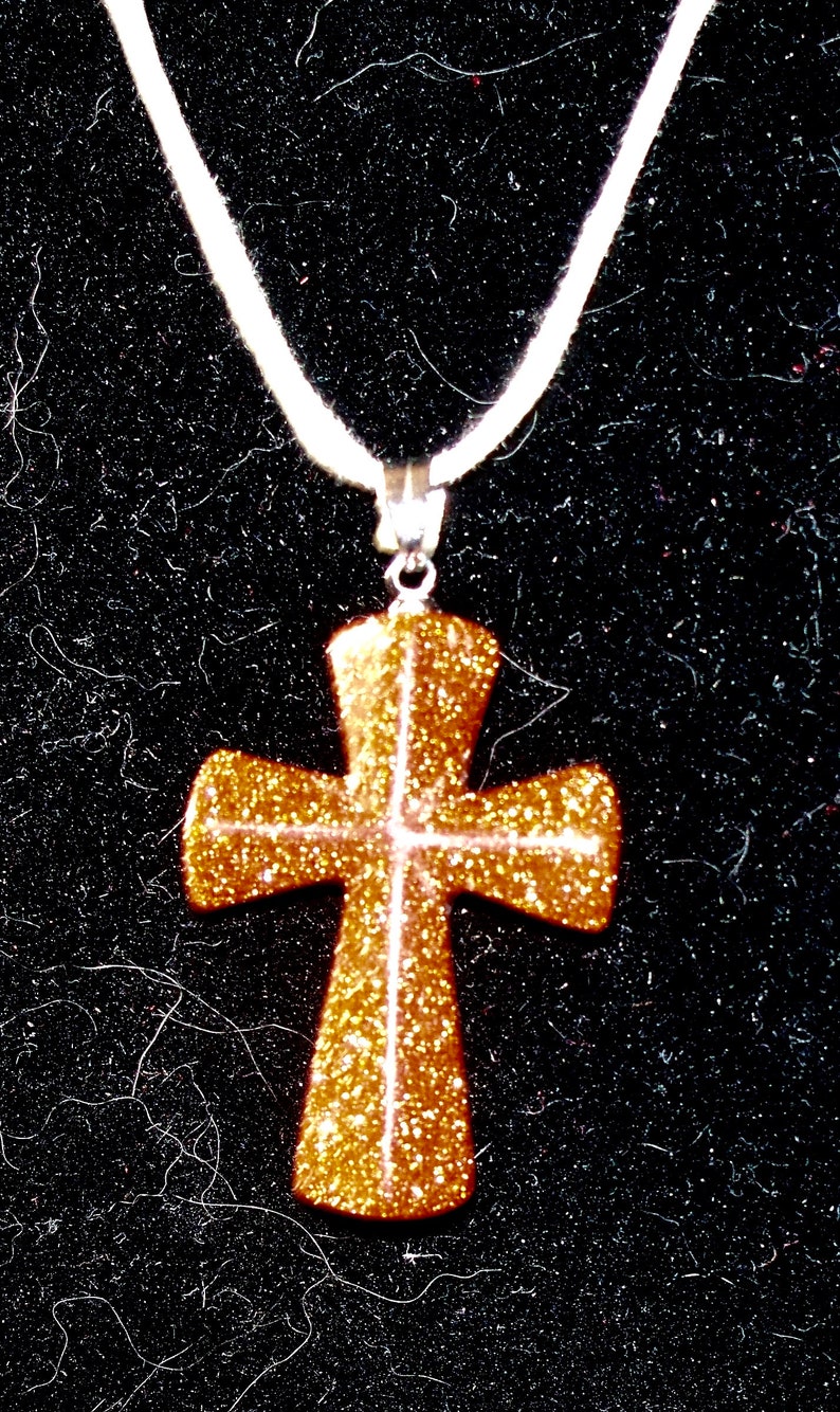 Carved Goldstone cross on cotton cord