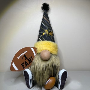 May include: A black and gold gnome wearing a hat with a team logo and holding a football that says "#1 FAN!"
