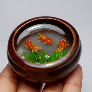 Miniature clay goldfish in the pond with real dried plant