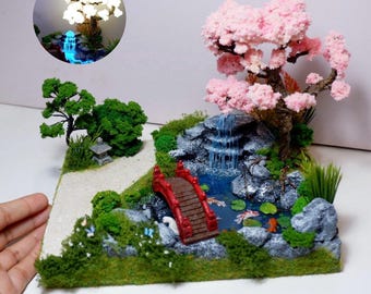 Diorama de estanque japonés en miniatura con carpas koi, cerezo en flor resplandeciente y puente con cascada.