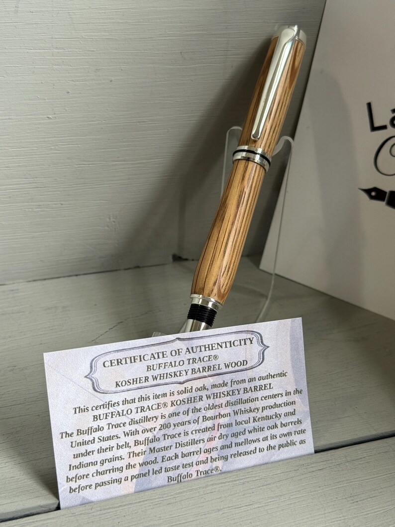 May include: A wooden pen with a silver clip and accents, made from Buffalo Trace Kosher Whiskey Barrel wood. The pen is displayed with a certificate of authenticity.