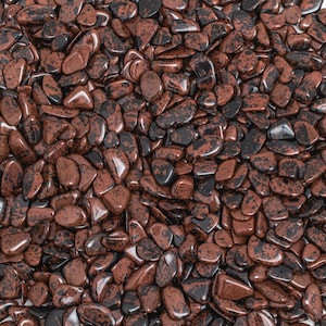 May include: A close-up view of a large quantity of red and black jasper tumbled stones. The stones are smooth and polished, with a variety of shapes and sizes.