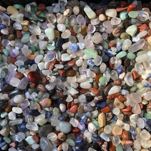 May include: A collection of colourful tumbled stones, including clear quartz, amethyst, rose quartz, and blue agate. The stones are various sizes and shapes, and they are perfect for crafting, meditation, or home decor.