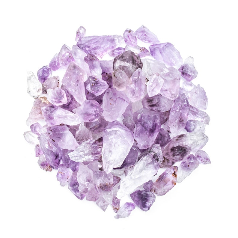 May include: A large pile of amethyst crystals in various sizes and shapes. The crystals are a light purple color and have a natural, rough texture.
