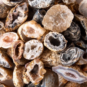 May include: A collection of agate crystals with various shapes and sizes. The crystals are a mix of white, brown, and gray with natural patterns and textures.