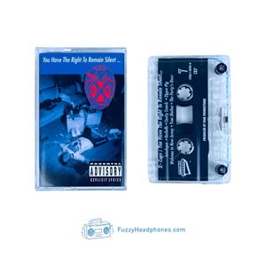 May include: Two cassette tapes. One has a blue and white cover with the text "You Have The Right To Remain Silent..." and "Parental Advisory Explicit Lyrics." The other tape is transparent with black text. The website FuzzyHeadphones.com is at the bottom.