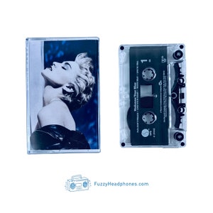 May include: A clear plastic cassette tape case with a black cassette tape inside. The cassette tape has the title "Madonna/True Blue" and the song titles "Papa Don't Preach", "Open Your Heart", "White Heat", and "Live to Tell".