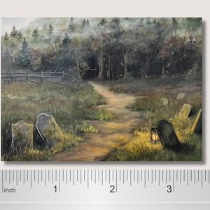 May include: A rectangular print depicting a misty graveyard scene with a dirt path leading into a dark forest. Several weathered tombstones are scattered in the grass, and a glowing lantern sits near one. A ruler shows the print is 4 inches wide.