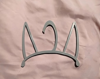May include: A gray plastic hanger shaped like a cat's head with ears. The hanger has a hook on the top for hanging clothes.