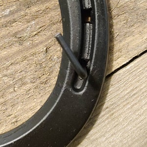 May include: Black horseshoe with a metal nail sticking out of the top hole.