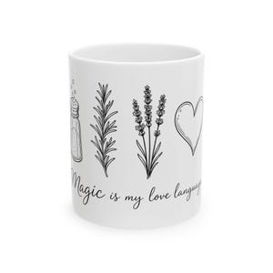 May include: A white ceramic mug featuring black line art illustrations of a salt shaker, a sprig of rosemary, a lavender stalk, and a heart. Below the illustrations, the text reads, Magic is my love language, in a cursive script font.