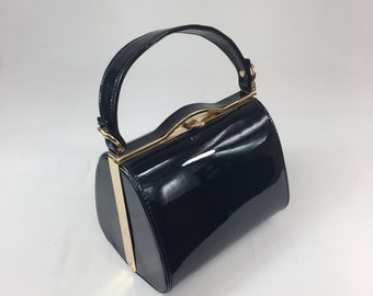 May include: A black patent leather handbag with a gold-toned clasp and handle.