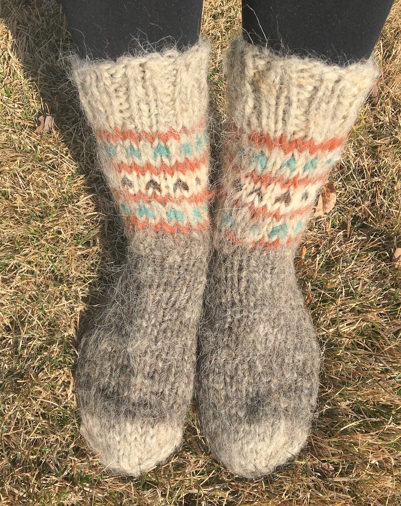 May include: A pair of grey wool socks with a white cuff and colourful geometric patterns. The socks are fuzzy and have a rustic look.