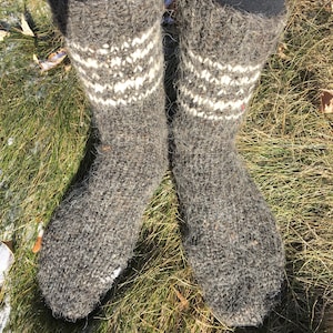 May include: A pair of gray wool socks with white knit patterns. The socks are worn and have a fuzzy texture.