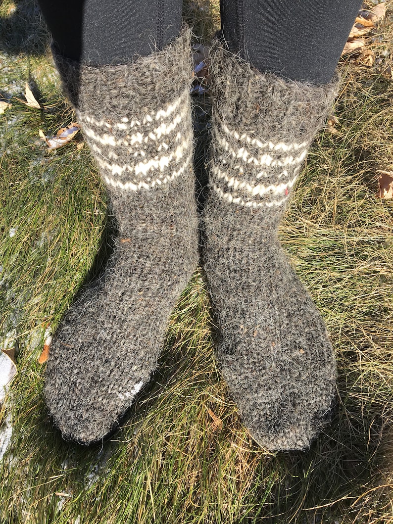 May include: A pair of gray wool socks with white knit patterns. The socks are worn and have a fuzzy texture.