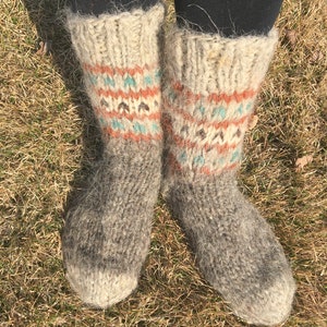 May include: A pair of grey wool socks with a colourful geometric pattern around the ankle. The socks are fuzzy and have a rustic look.