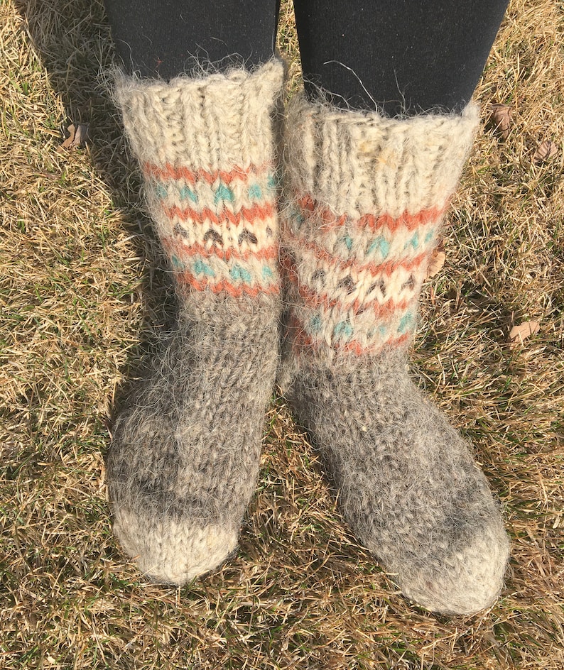 May include: A pair of grey wool socks with a colourful geometric pattern around the ankle. The socks are fuzzy and have a rustic look.