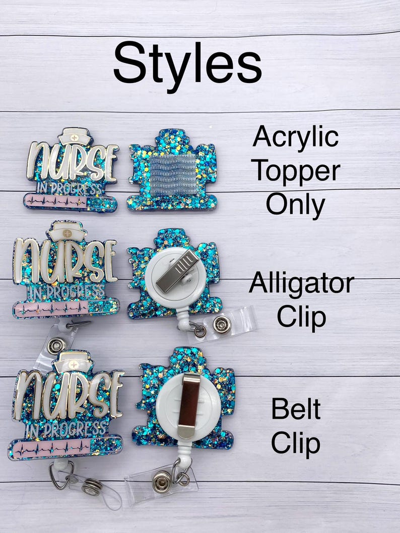 May include: Three different styles of nurse badge reels with a blue and turquoise glitter background. The text "Nurse in Progress" is on each reel. The first reel is an acrylic topper only. The second reel has an alligator clip. The third reel has a belt clip.
