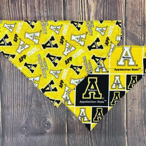 May include: Two triangular pet bandanas featuring Appalachian State University branding. One bandana has a yellow background with a repeating black and white letter A logo and the text APP STATE. The other has a black and yellow grid pattern.