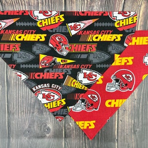May include: Two dog bandanas, one black with white and yellow Kansas City Chiefs logos and the other red with yellow Kansas City Chiefs logos.