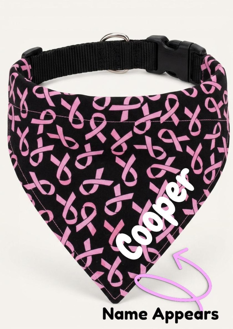 A black bandana with a pink ribbon pattern, featuring the name "Cooper" written in white on the right side.