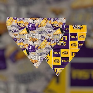 May include: Two dog bandanas, one with a grey background and a repeated pattern of a cartoon tiger wearing a purple jersey and holding a yellow megaphone, and the other with a yellow background and a repeated pattern of a purple square with a tiger head inside and the text "LSU" in yellow.