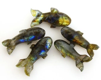 Puede incluir: Cinco figuras de peces de labradorita tallada. Los peces son grises con destellos iridiscentes azules, verdes y amarillos. Cada pez tiene una cola y aletas detalladas, dispuestas sobre un fondo blanco.
