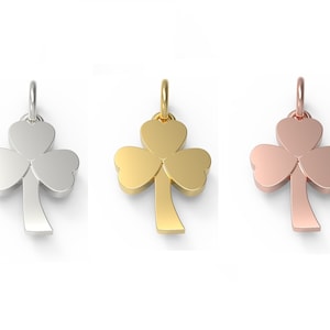 May include: Three shamrock pendants in silver, gold, and rose gold. Each pendant features a three-leaf clover design with a loop for a chain. The pendants are displayed against a white background.