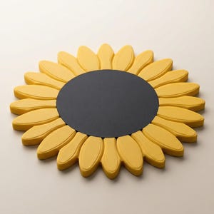 May include: A decorative sunflower-shaped object with a black center and yellow petals. The petals are rounded and arranged in a circular pattern. The object is likely made of a solid material and rests on a neutral surface.